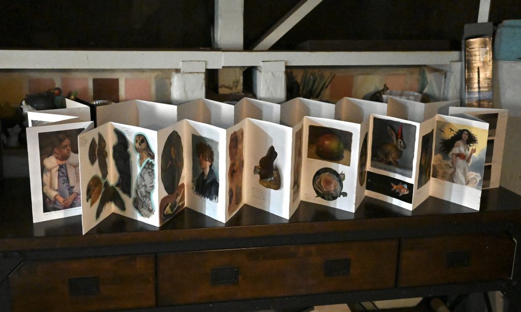 photo of an accordion-fold sketchbook expanded into a circle, with small paintings on each page